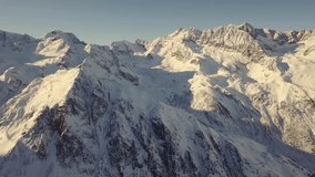 An aerial view shows snow-covered mountains under a clear sky and sunlight - Powered by Shutterstock - Get 15% off with code: PIKWIZARD15
