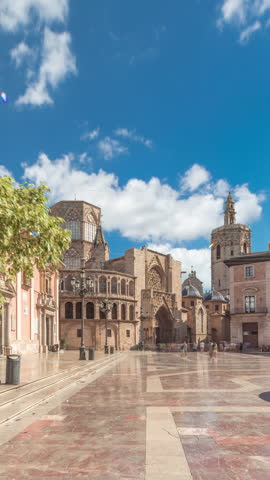 Panoramic timelapse hyperlapse of Valencia's Plaza de la Virgen, showcasing Turia Fountain, Cathedral and Basilica de la Virgen de los Desamparados in Spain's historic old town under a blue cloudy sky