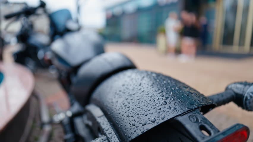 A CloseUp Shot of a RainDrenched Motorcycle Set Against an Urban Environment, Capturing Its Stylish Essence