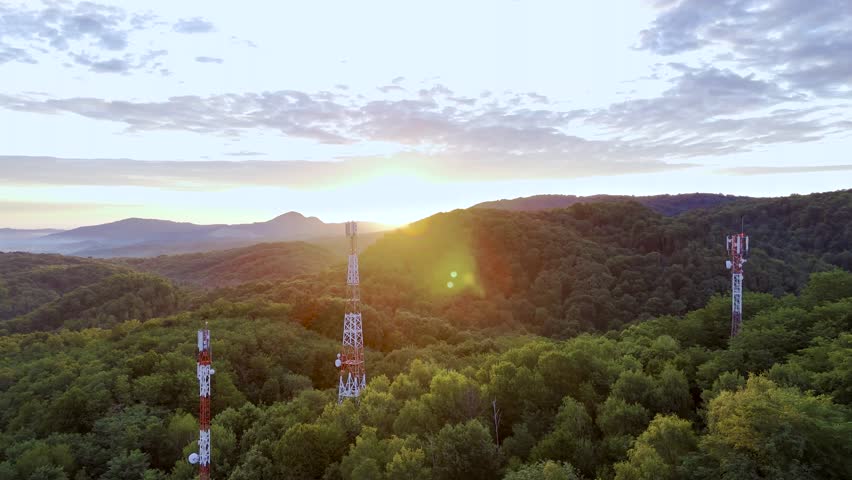 Aerial of three cellular telecom towers in green landscape at sunrise, using 4G and 5G technology for communication - Powered by Shutterstock - Get 15% off with code: PIKWIZARD15