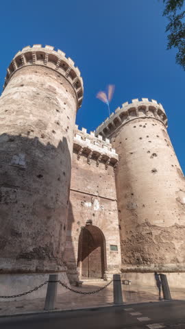 Towers of Quart timelapse hyperlapse in Valencia, Spain. Historical medieval gate, part of the ancient city walls. Popular landmark with a rich cultural heritage. Blue sky and street traffic scene.