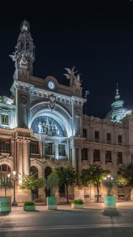 Historic Post Office (Palau de les Comunicacions) in Valencia night timelapse hyperlapse at City Hall Square (Plaza del Ayuntamiento). Ornate facade and street traffic in the Spanish city center.