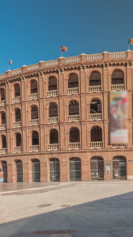 Panorama showing Bullring of Valencia (Plaza de Bous) timelapse and Bullfighting Museum, near Nord station. People walking around the historic amphitheater with a blue sky backdrop. Valencia, Spain.