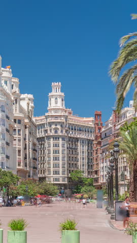 Valencia City Hall (Ajuntament de Valencia) timelapse in Plaza de Ayuntamiento. Historic building entrance tower under a blue sky. People strolling the main square in Spain