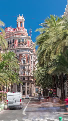 Timelapse of Banco de Valencia headquarters, historic landmark in Valencia, Spain. Stunning architecture with palm-lined street and busy traffic under a bright blue sky. Urban financial district scene