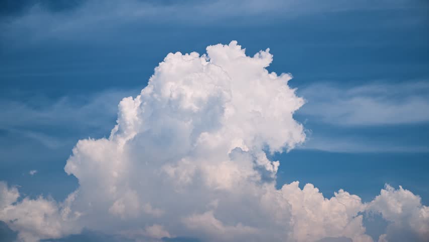 Upward view of fluffy white clouds drifting across a bright blue summer sky in Tamsui, New Taipei, Taiwan.