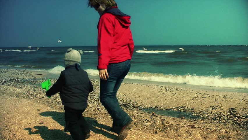 Mother and little boy running on the beach, slow motion