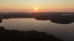 Serene lake at sunrise, with calm water reflecting the orange and pink hues of the sky. Mist gently rises from the forested shoreline, creating a peaceful and tranquil morning atmosphere. Aerial view. - Powered by Shutterstock - Get 15% off with code: PIKWIZARD15