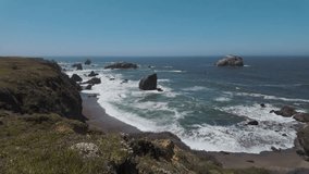 A rugged coastline with dark cliffs overlooks a blue ocean with white waves crashing against scattered rock formations in california coast - Powered by Shutterstock - Get 15% off with code: PIKWIZARD15