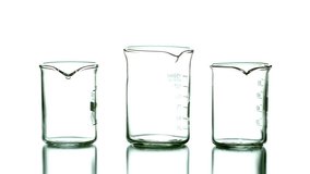 Green drop falling into middle beaker starting three streams overflowing and pooling on table. Science, experimentation, chemistry, fluid dynamics, minimalism, abstract, innovation - Powered by Shutterstock - Get 15% off with code: PIKWIZARD15