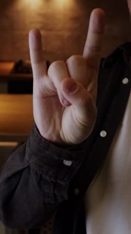 Man showing rock hand gesture symbolizing love for heavy metal music style. Punk rock