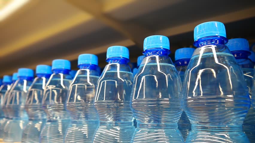 Many nice blue bottles of potable water standing in a row on a supermarket display