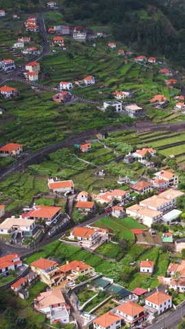 Aerial of traditional terrace village Sao Vicente, Madeira Island, Portugal. Small houses and gardens among a green mountain landscape in stormy weather.