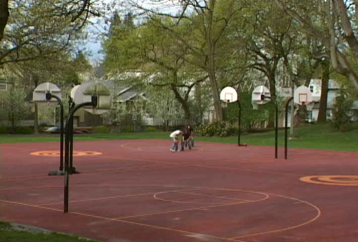 Group of men play basketball at park as time lapse.