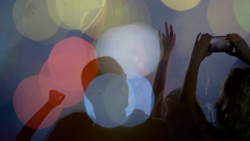 Audience members lifting smartphones, waving at dim music venue with bokeh lights, capturing singer. Concert, nightlife, silhouettes, vibrant, energy, ambiance, entertainment