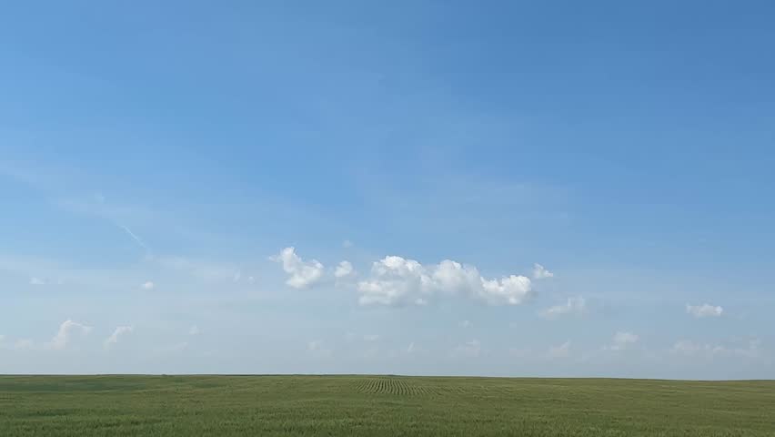 Driving past scenic farmland fields in the rural countryside, capturing open skies, agricultural landscapes, crops, grasslands, and peaceful farm views along a quiet country road in Alberta, Canada.