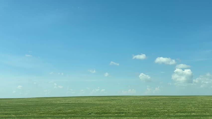 Driving past scenic farmland fields in the rural countryside, capturing open skies, agricultural landscapes, crops, grasslands, and peaceful farm views along a quiet country road in Alberta, Canada.