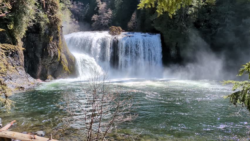 Lower Lewis Falls flowing between rocky cliff faces and falling into a tranquil blue pool.