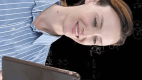 Animation of a Caucasian woman using her tablet with floating mathematics formulae on black background. Global economy and technology concept digital composite - Powered by Shutterstock - Get 15% off with code: PIKWIZARD15