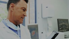 Middle-aged doctor scrolling tablet, activating medical data overlay while viewing positive metrics. Healthcare, technology, medical, analytics, innovation, professionalism, diagnostics - Powered by Shutterstock - Get 15% off with code: PIKWIZARD15