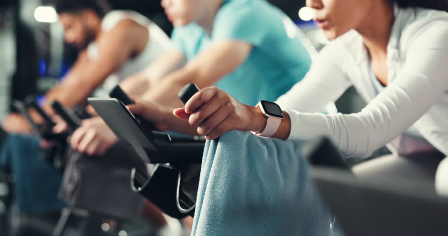Spin class, fitness and hands of person in gym for cycling machine, wellness and cardio workout. Stationary bike, exercise and performance with people in sports center for training, health and club