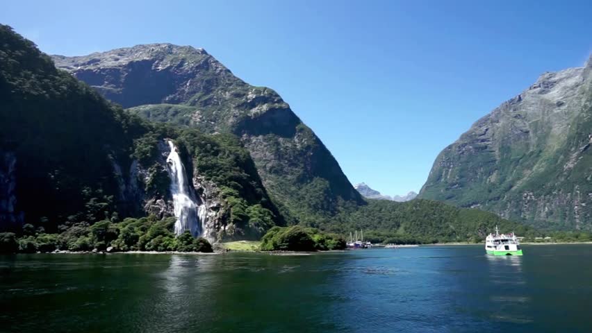 Milford sound with waterfall flowing into the lake in new zealand