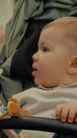 Vertical Screen: A young mother carefully feeds her baby a piece of bread while riding on the subway. The environment shows daily public transport life in the city.