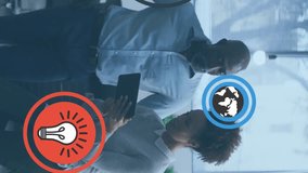 Animation of multiple icons over diverse coworkers discussing report on digital tablet in office. Digital composite, technology, ideas, business, globalization, planning, teamwork concept. - Powered by Shutterstock - Get 15% off with code: PIKWIZARD15