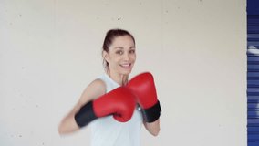 Professional female boxer practicing powerful punches while wearing red boxing gloves against pristine white background, demonstrating athletic prowess and intense training technique - Powered by Shutterstock - Get 15% off with code: PIKWIZARD15
