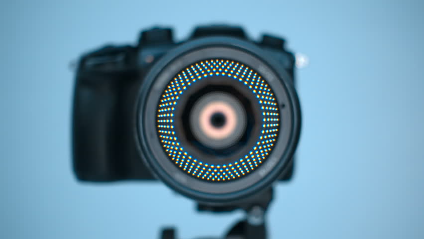 A professional camera on a tripod with an expensive lens with an aperture of 1.5 and a focal length of 85 mm, which reflects the ring LED light. Closeup. Macro. Shallow depth of field. Shot in motion