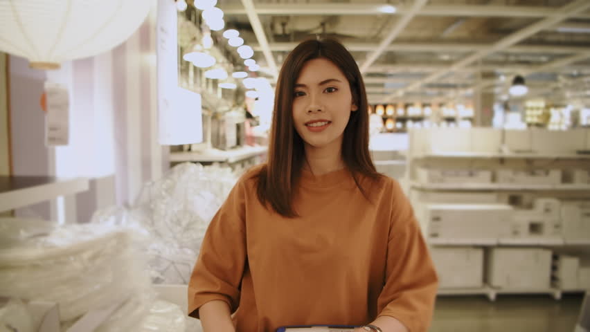 Shopping concept of 4k Resolution. Asian woman choosing a lamp in a shopping mall.