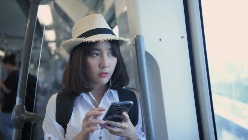Tourism concept of 4k Resolution. A beautiful girl is playing on the phone while traveling with the electric train.