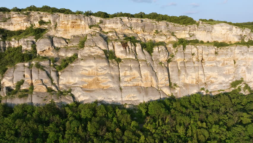 Limestone rock cliff with carved Madara Rider monument seen from drone, green summer vegetation, countryside landscape of northeast Bulgaria, historical symbol, UNESCO World Heritage, ancient travel