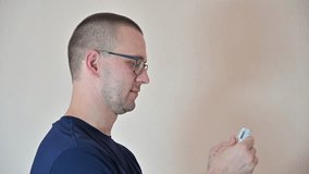 A short-haired man with eyeglasses uses an asthma inhaler, placing it in his mouth and taking a deep breath. The scene illustrates a typical usage moment for respiratory relief. - Powered by Shutterstock - Get 15% off with code: PIKWIZARD15