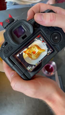 Vertical screen hands hold camera filming delicious khachapuri in cozy restaurant warm tones soft light focus on food authentic mood and appetizing atmosphere