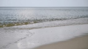 Young woman with light skin, black swimsuit, strolling along Baltic Sea. Sunlit waves gently touch sandy shore calm, serene atmosphere. Low-angle view highlights tranquil seascape - Powered by Shutterstock - Get 15% off with code: PIKWIZARD15