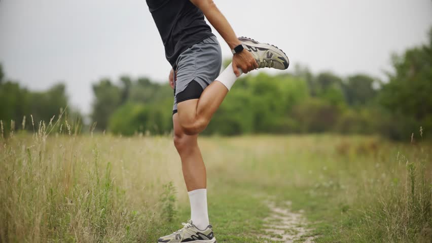Athlete Warming Up Before Exercise. Male Runner Stretching Quadriceps. Fitness Training Pre-Workout Routine. Flexibility And Mobility. Exercise Preparation Dynamic Stretching. Cardio Preparation Run