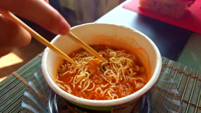 Eating Instant Ramen Noodles. Spicy Noodle Soup Asian Fast Food. Budget-Friendly Lunch College Student Life. Comfort Food Convenient Meal. Busy Lifestyle Savory Dish. Enjoy A Quick Meal. Instant Ramen