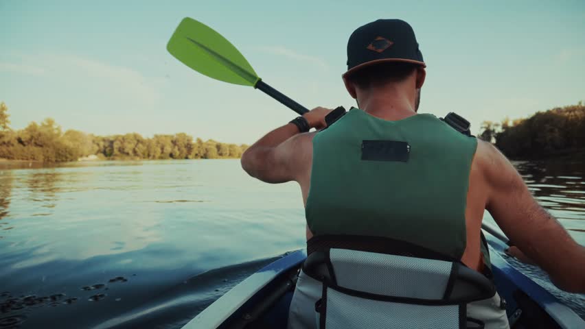 Man Kayaking On Serene River With Paddle. Active Paddler Outdoor Water Sport Recreation. Summer Adventure Activity. Peaceful Nature Retreat, Solo Kayaking Experience Paddle Stroke Calm Water Excursion