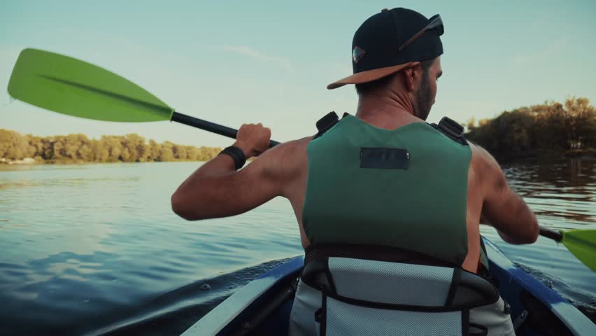 Man Kayaking On Serene River With Paddle. Active Paddler Outdoor Water Sport Recreation. Summer Adventure Activity. Peaceful Nature Retreat, Solo Kayaking Experience Paddle Stroke Calm Water Excursion