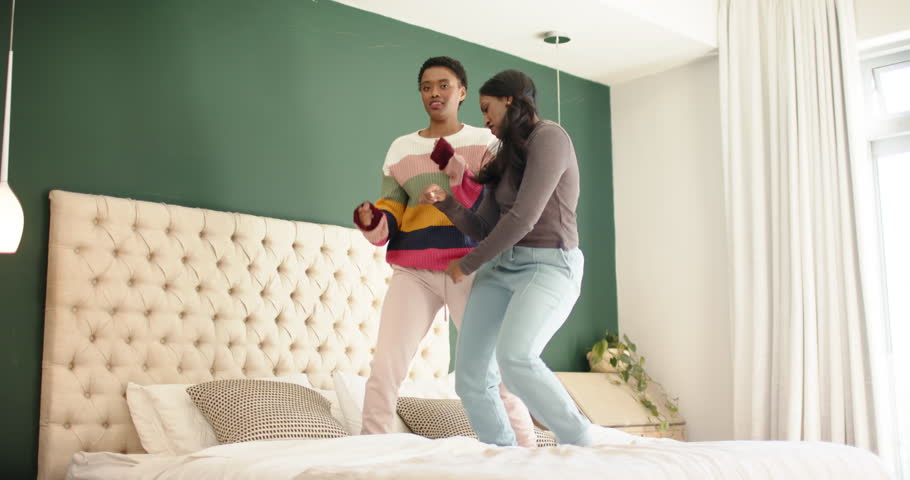 Diverse female friends stepping onto bed, testing mattress by bouncing and syncing dance moves. Friends, dance, rhythm, playful, casual, vibrant, lifestyle