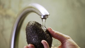 A man rinses a fresh avocado under running water in the kitchen sink, close-up view. Process of washing vegetables before cooking.

 - Powered by Shutterstock - Get 15% off with code: PIKWIZARD15