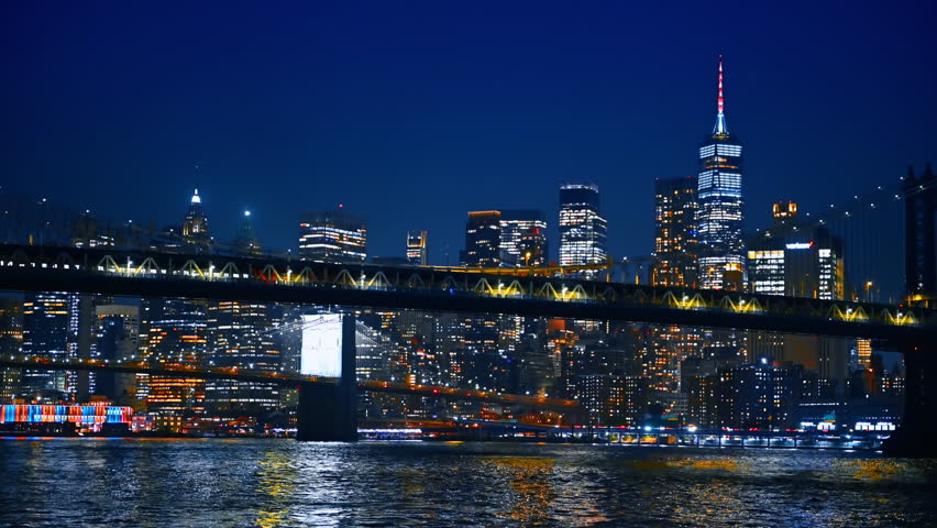 Vibrant nightlife of modern metropolis. Low angle view on the Manhattan Bridge and New York skyline from the East River waterscape.