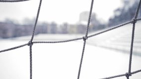 Winter view of a football stadium blanketed in snow, seen through the mesh of a soccer goal. Empty field in seasonal conditions. Outdoor sports venues. - Powered by Shutterstock - Get 15% off with code: PIKWIZARD15