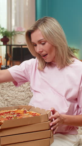 Pregnant middle-aged woman at home ordering pays pizza order on smartphone banking app satisfied waiting for meal. Caucasian girl on sofa receiving delivery from courier dinner anticipation treat.