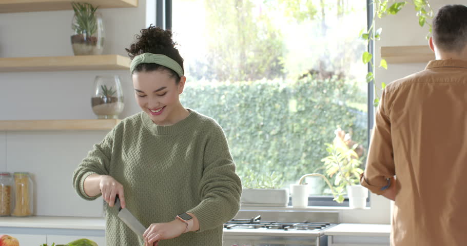 Diverse couple chopping vegetables at kitchen island after missing celery triggers partner handoff. Fresh produce, meal prep, culinary, modern, lifestyle, teamwork, wellness
