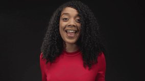 Woman flips long curly hair and raises both hands in dynamic studio dance pose with smiling face; happiness. - Powered by Shutterstock - Get 15% off with code: PIKWIZARD15