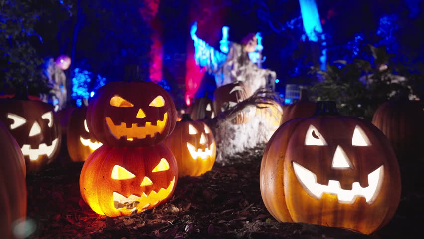 A colorful display of intricately carved pumpkins is illuminated at night, creating an enchanting Halloween atmosphere filled with mystery and charm, inviting all to enjoy the festive scene