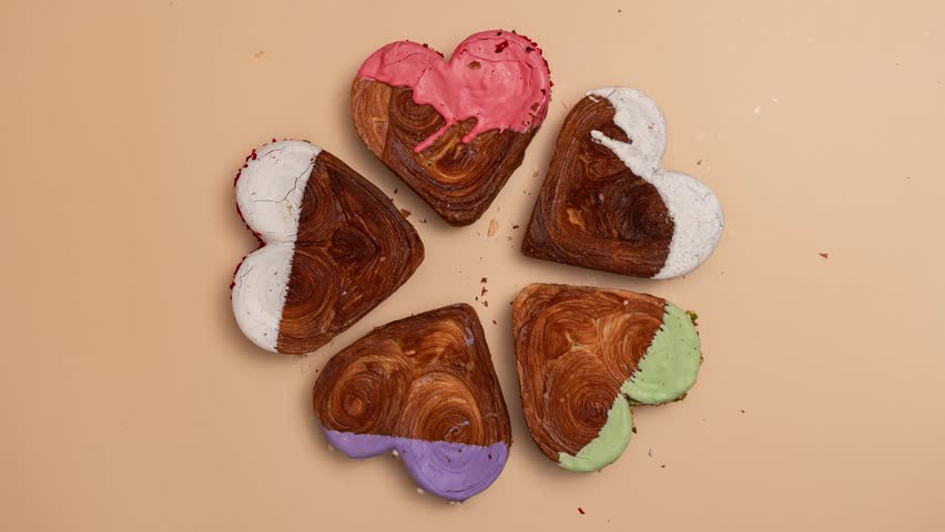 Stop motion Creative idea Valentine's Day flat lay top view Holiday celebration Heart shaped different variety flavor croissants on beige background. Puff pastry new trendy sweet dessert bakery
