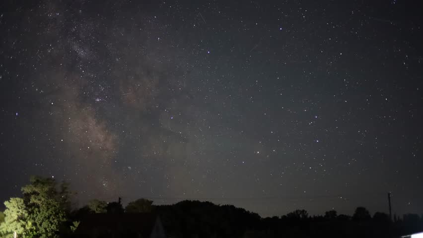 Bright milky way arching across a dark night sky over trees and houses - Powered by Shutterstock - Get 15% off with code: PIKWIZARD15
